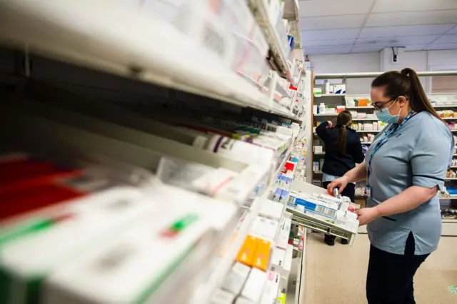 A pharmacy worker sorts through shelves