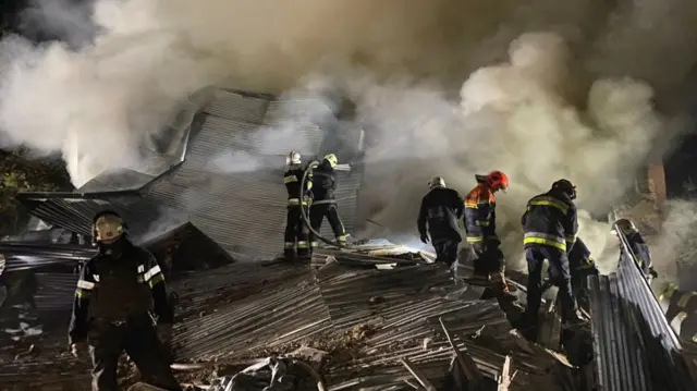 Workers amid damaged metal and smoke in Kharkiv