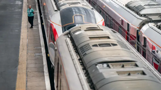 A train station worker stands on a platform at Kings Cross Station