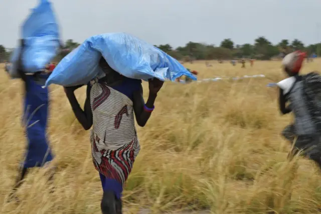 Villagers collect food aid dropped from a plane in gunny bags from a plane onto a drop zone at a village in Ayod county, South Sudan