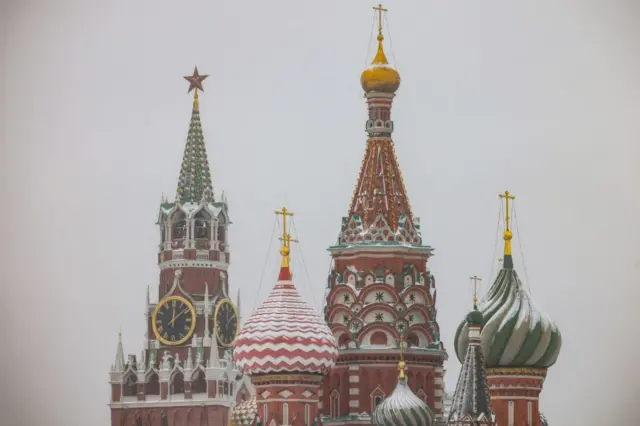 A picture shows the Kremlin's Spasskaya tower and St. Basil's Cathedral as it snows in Moscow on December 7, 2021.