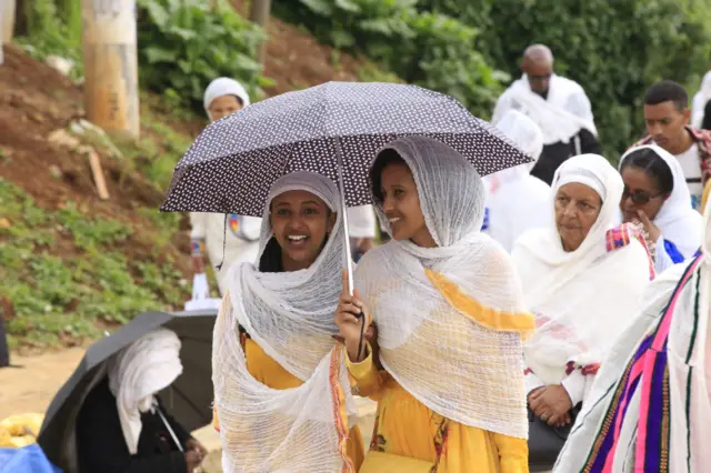 Ethiopian women under an umbrella, smiling