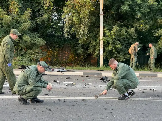 Investigators work at the site of a suspected car bomb attack that killed Darya Dugin