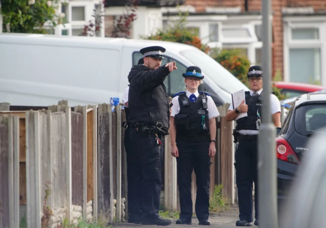 Police officers stand outside property on Kingsheath Avenue