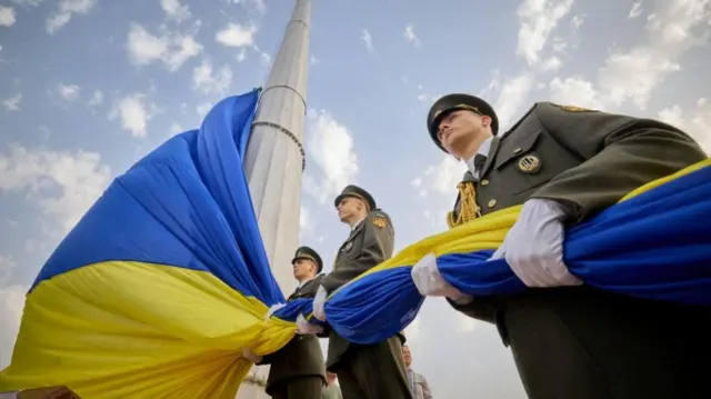 The flag is hoisted up a pole in Kyiv