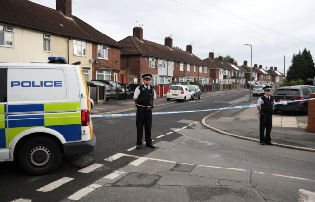 Police stand guard outside a home on Kingsheath Avenue