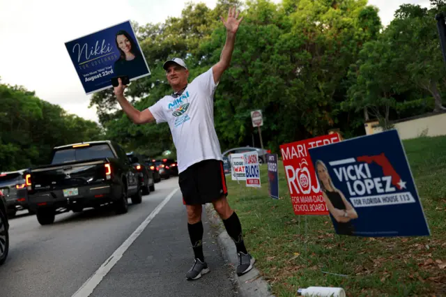 Jim Fried campaigns for his niece Nikki Fried, holding up a sign by the roadside