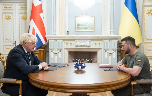 Johnson and Zelensky sit across the table from each other for talks, in front of their respective country's flags