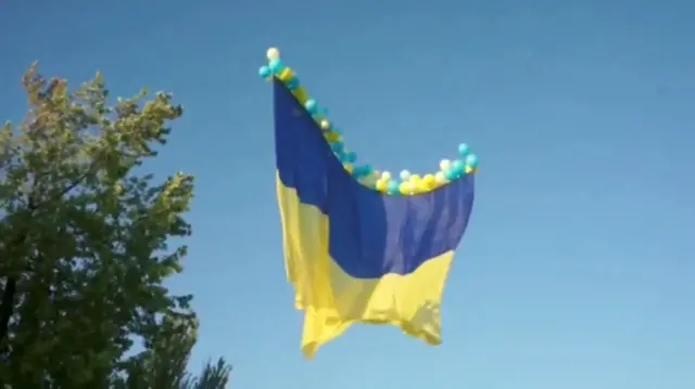 A Ukrainian flag is raised with balloons on Independence Day, in Avdiivka, Donetsk region, Ukraine