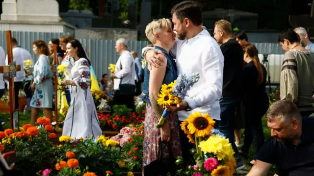 A man and woman embrace at a ceremony at the graves of fallen soldiers in Lychakiv cemetery