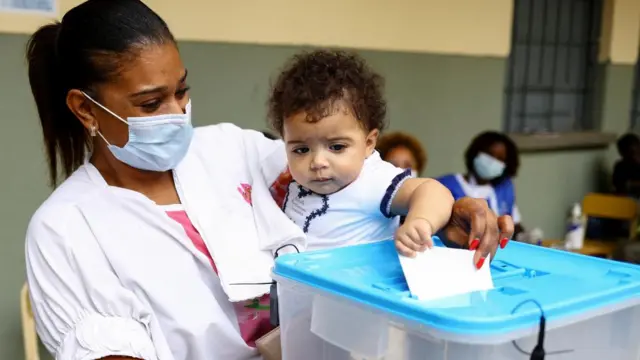 A woman looks on as her baby casts her vote in a ballot box during the general election at Nzinga Mbandi school in the capital Luanda, Angola August 24, 2022