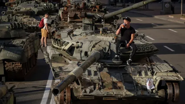 A man drinks a coffee on a destroyed Russian tank on Kyiv's main street Khreshchatyk