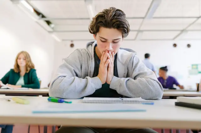 a student looking worried sat in an exam hall