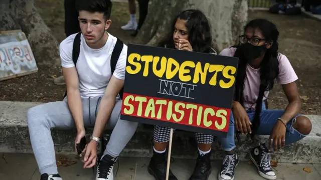 Students sat with placard saying "students not statistics"