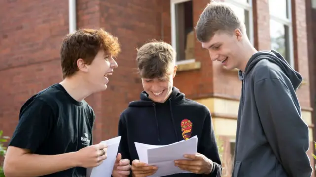 Three children smile and laugh as they receive their exam results