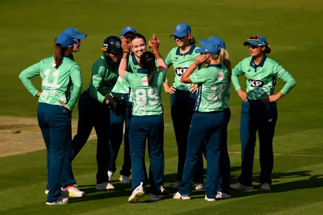 Mady Villiers and Shabnim Ismail high-five celebrating a wicket, surrounded by their Oval Invincibles teammates