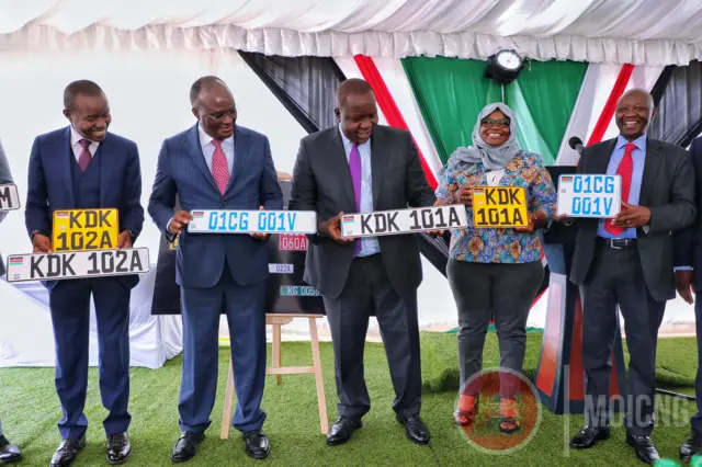 Officials hold up new number plates