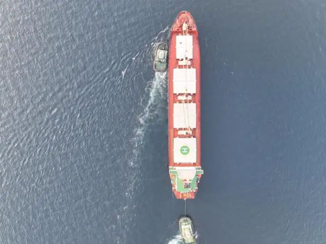 Aerial shot of ship accompanied by tugs arriving into port in Djibouti