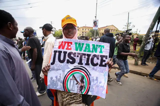 A Kenyan woman holds a placard that says "We want Justice" outside the Supreme Court registry at the Milimani Law Courts in Nairobi during the filing of an election petition