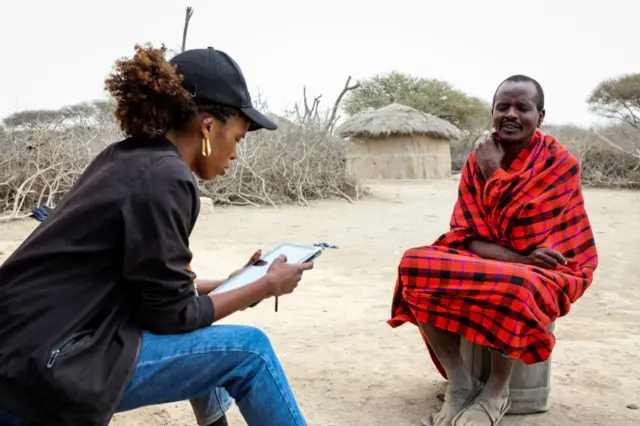 A census enumerator (L) listens to a Maasai man during the population and housing census,