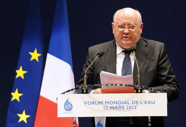 Mikhail Gorbachev speaks next to an EU flag