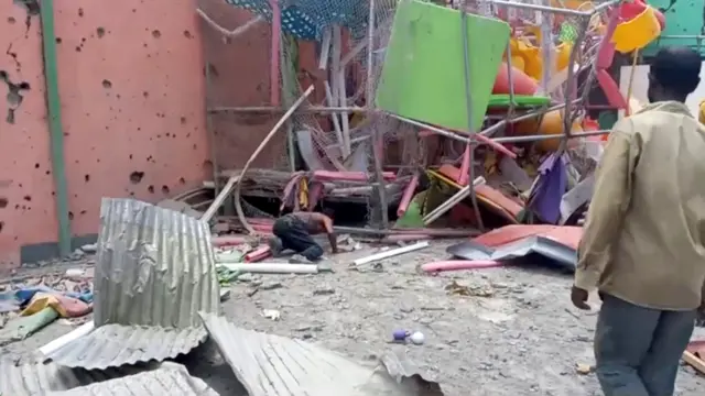 A man crouches to inspect a damaged playground following an air strike in Mekelle, the capital of Ethiopia's northern Tigray region, August 26, 2022 i