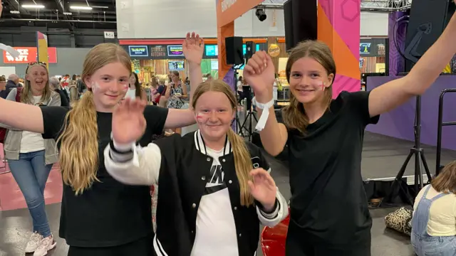 Freya, Darcy and Ruby cheering with flags on their faces