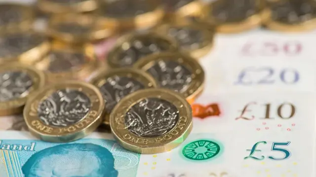 A pile of pound coins and UK banknotes