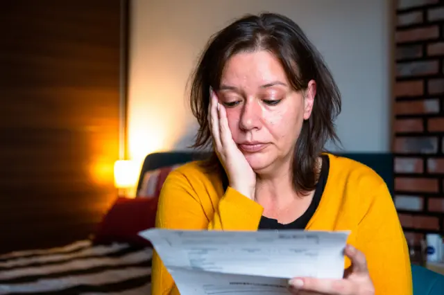 A woman looks concerned while checking her energy bills