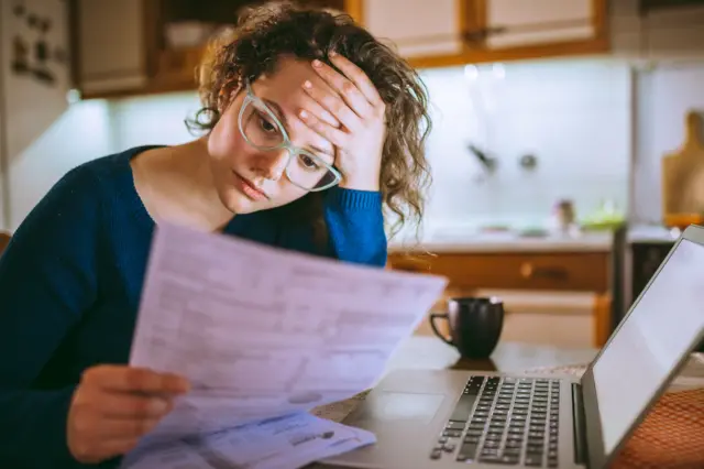 A woman looks stressed by a bill