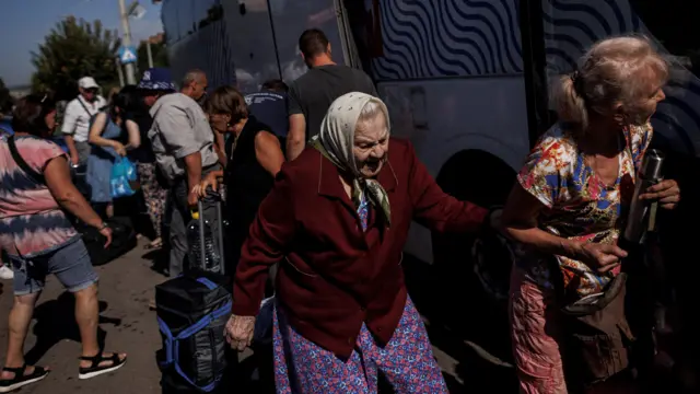 An elderly woman is assisted to board a bus to Germany from Kramatorsk