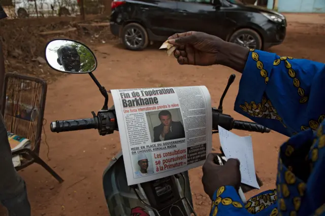 A man buys a newspaper whose headlines announce a major drawdown of France's military presence in the Sahel, where forces have been battling jihadist insurgents for nearly a decade, in Bamako on June 11, 2021.