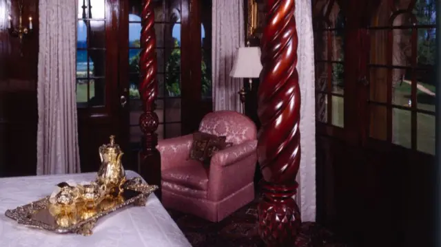 a photo of one of the bedrooms, with a gold dinner service on the four-poster bed