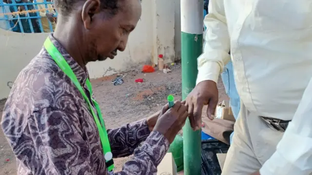 An electoral official marking someone's nail in north-eastern Kenya