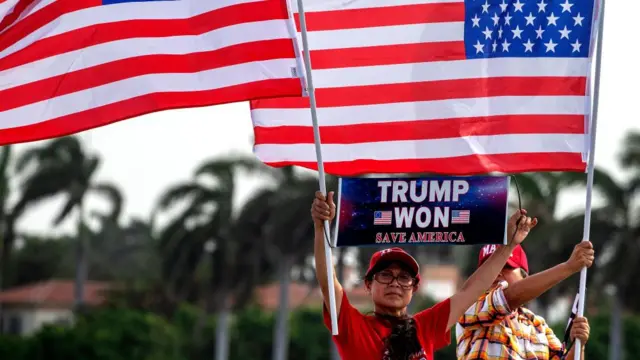 Supporters of former US President Donald Trump stand outside Trump's Mar-a-Lago residence holding US flags