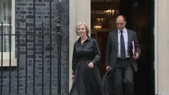 Liz Truss exiting through the front door of Number 10, wearing black. (10 September)