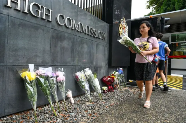 A woman leaves flowers at the British High Commission