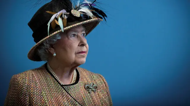 A picture of the Queen wearing a feathered hat