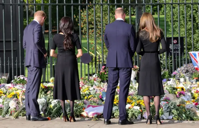 Prince Harry, Duke of Sussex, Meghan, Duchess of Sussex, Prince William, Prince of Wales and Catherine, Princess of Wales look at floral tributes laid by members of the public on the Long Walk at Windsor Castle on September 10, 2022 in Windsor, England.