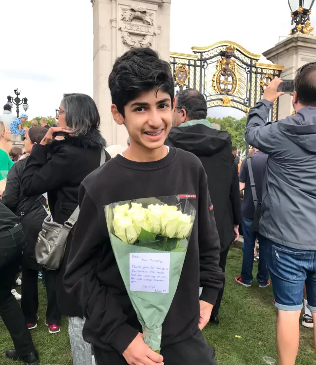 Thirteen-year-old Kian holds a bunch of flowers outside Buckingham Palace