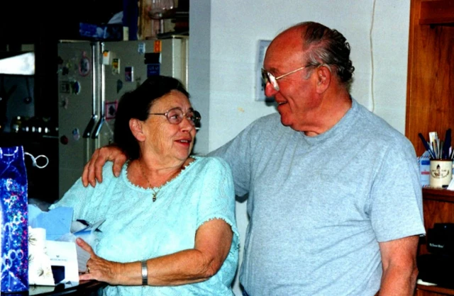 Liz's parents celebrate Christmas together at their home sorting out presents and hugging in the kitchen