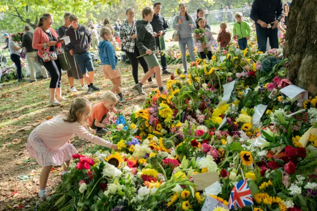 Floral tributes are being brought to a temporary memorial garden in Green Park on 11 September 2022