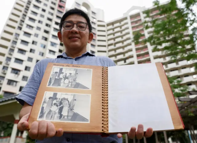 Researcher Jerome Lim, 57, shows photos of Queen Elizabeth"s 1972 visit to his and his parents" public housing apartment,