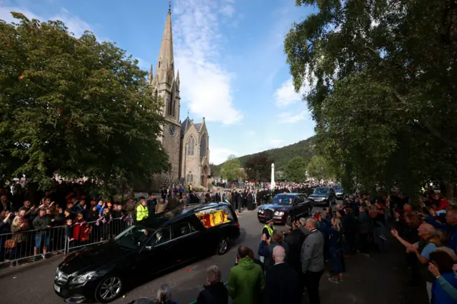 People watch the coffin as it passes through Ballater