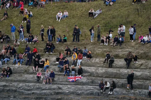 People wait to view the hearse