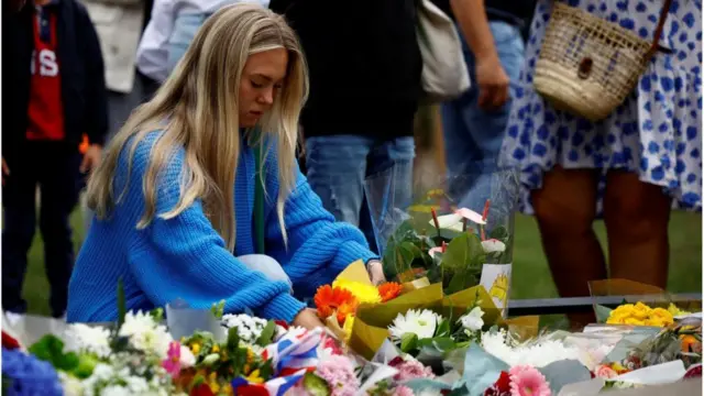 A mourner lays some flowers