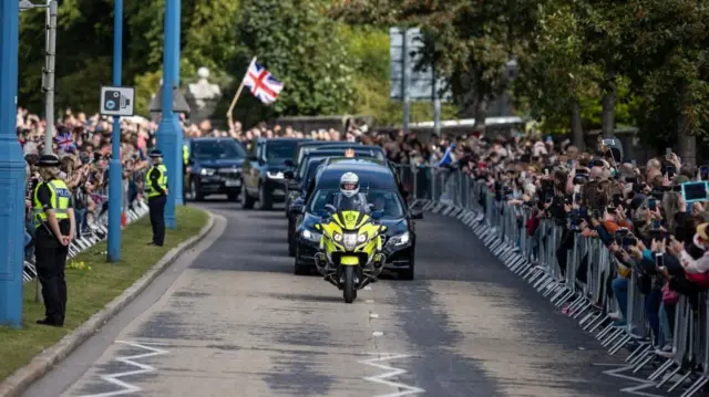 The hearse carrying the coffin of Queen Elizabeth II, draped with the Royal Standard of Scotland, passing through Aberdeen as it continues its journey to Edinburgh from Balmoral