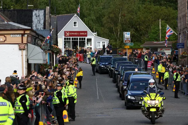 People line the street as the hearse carrying the coffin passes through