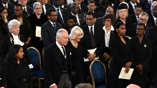 MPs and peers look on as King Charles and the Queen Consort arrive in Westminster Hall