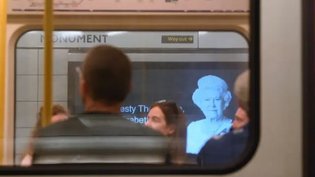 London Underground train passengers pass a billboard image of Britain"s Queen Elizabeth, following her death,